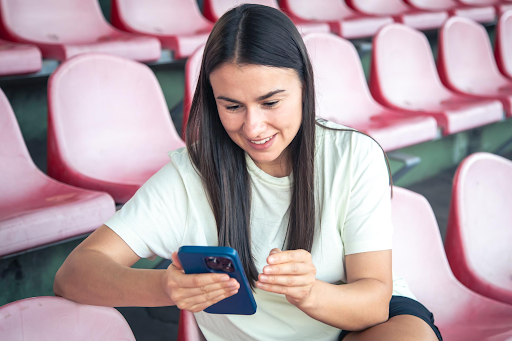 girl-sportswear-sitting-stadium-seats-using-smartphone